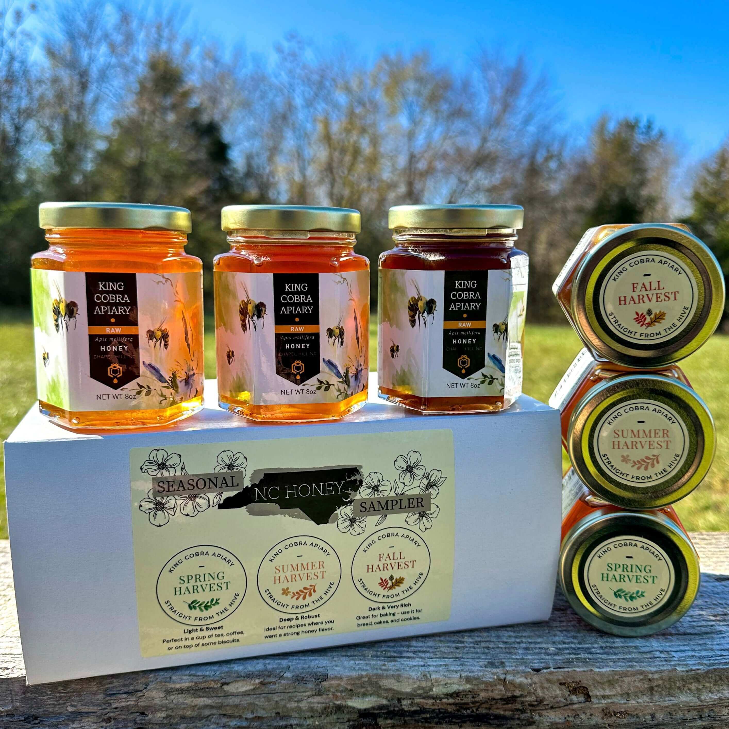 Gift Sets and eGift Cards featuring seasonal NC honey sampler jars on display outdoors.
